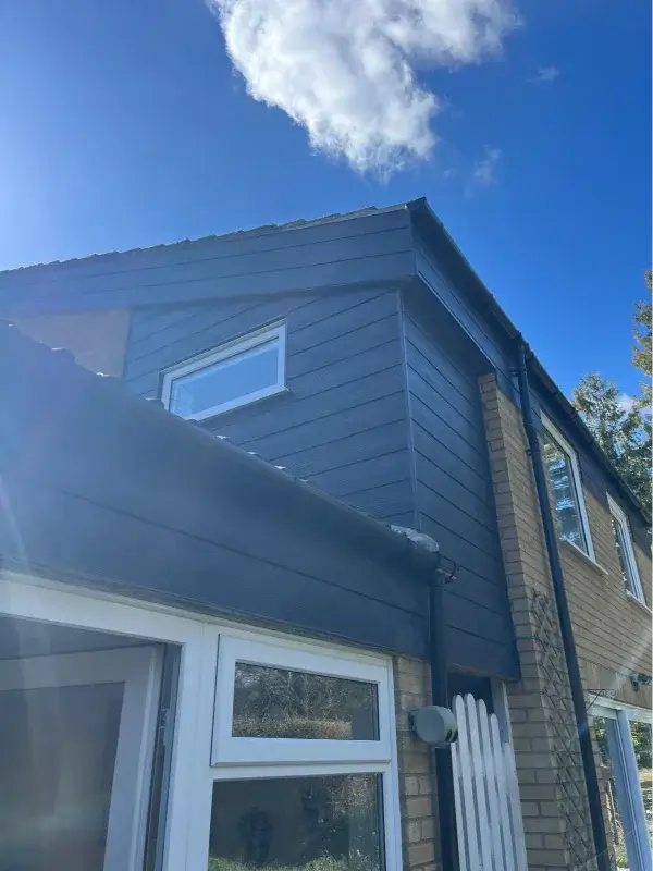 Dark grey horizontal cladding fitted to the upper storey around white-framed windows. By Norfolk Exterior Solutions.